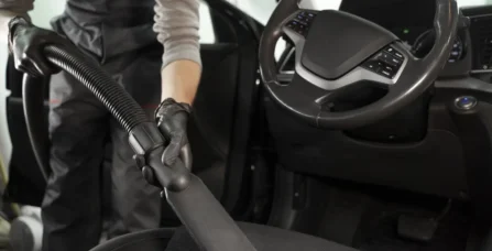 Професійна хімчистка салону авто: майстер ретельно очищує текстильне сидіння автомобіля за допомогою потужного пилосмока.